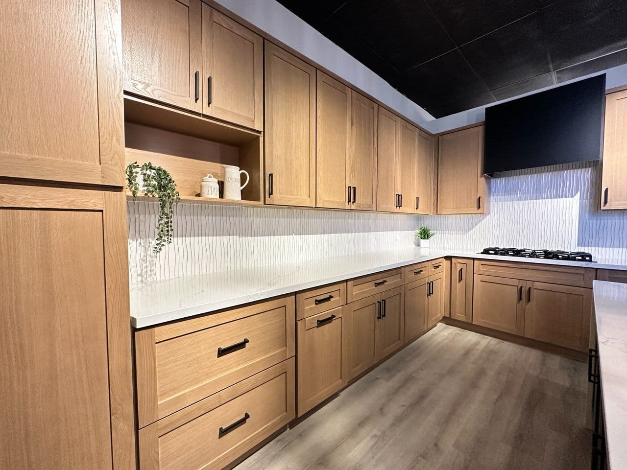 A kitchen with medium brown wood cabinets and white countertops.